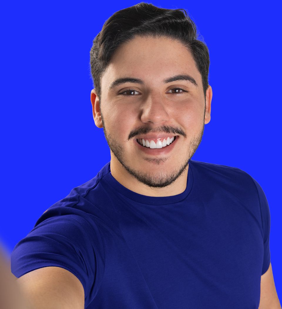 Alvinho Lira sorrindo, de camiseta azul, tirando uma selfie